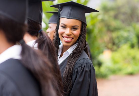 Pretty university graduate looking back at graduation ceremony